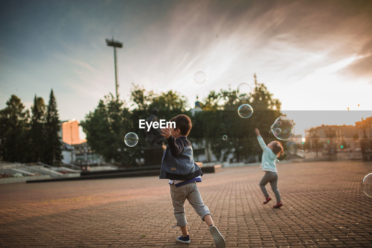 Full length of children playing against sky during sunset