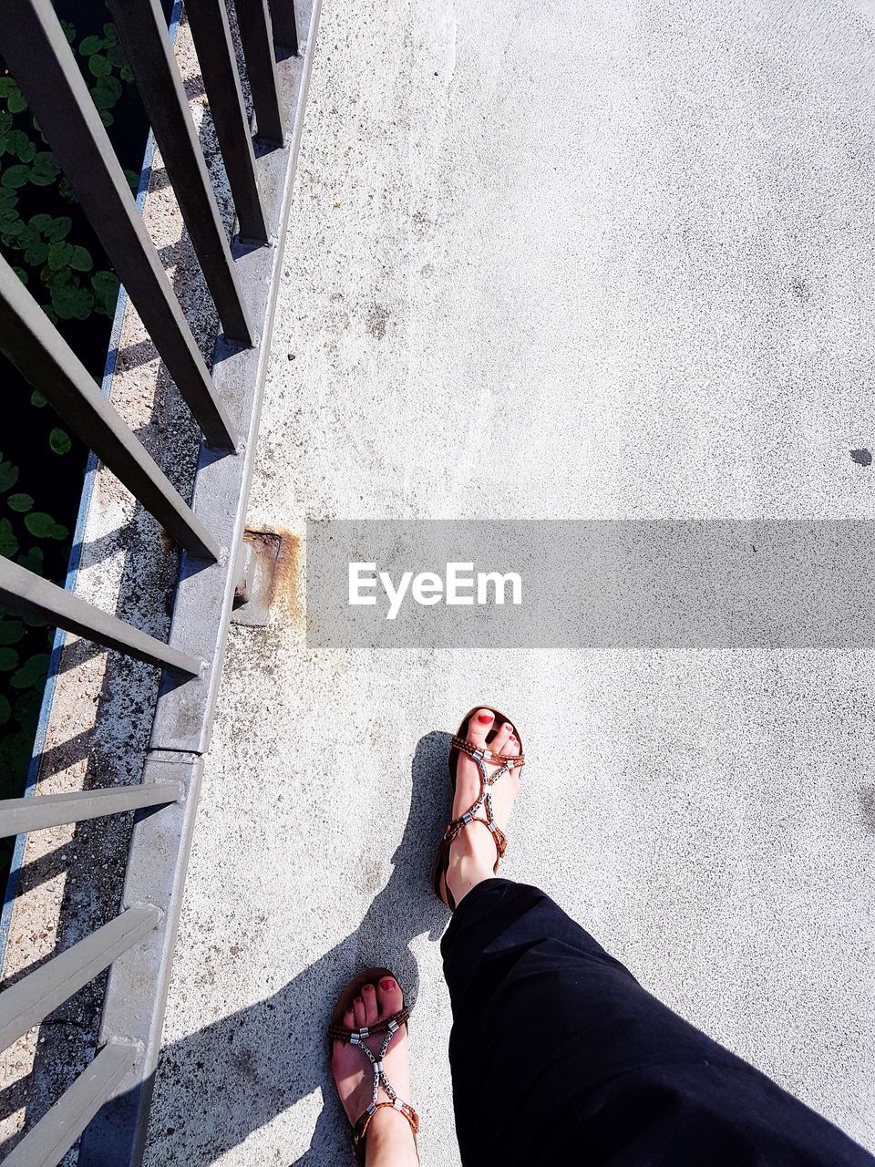 LOW SECTION OF WOMAN STANDING ON CONCRETE STAIRCASE