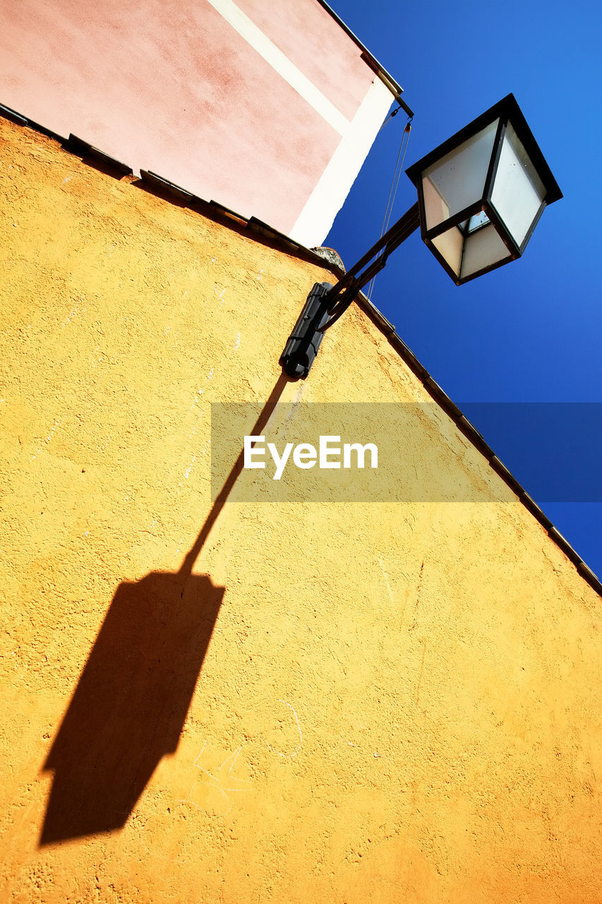 Low angle view of lantern on building against clear blue sky