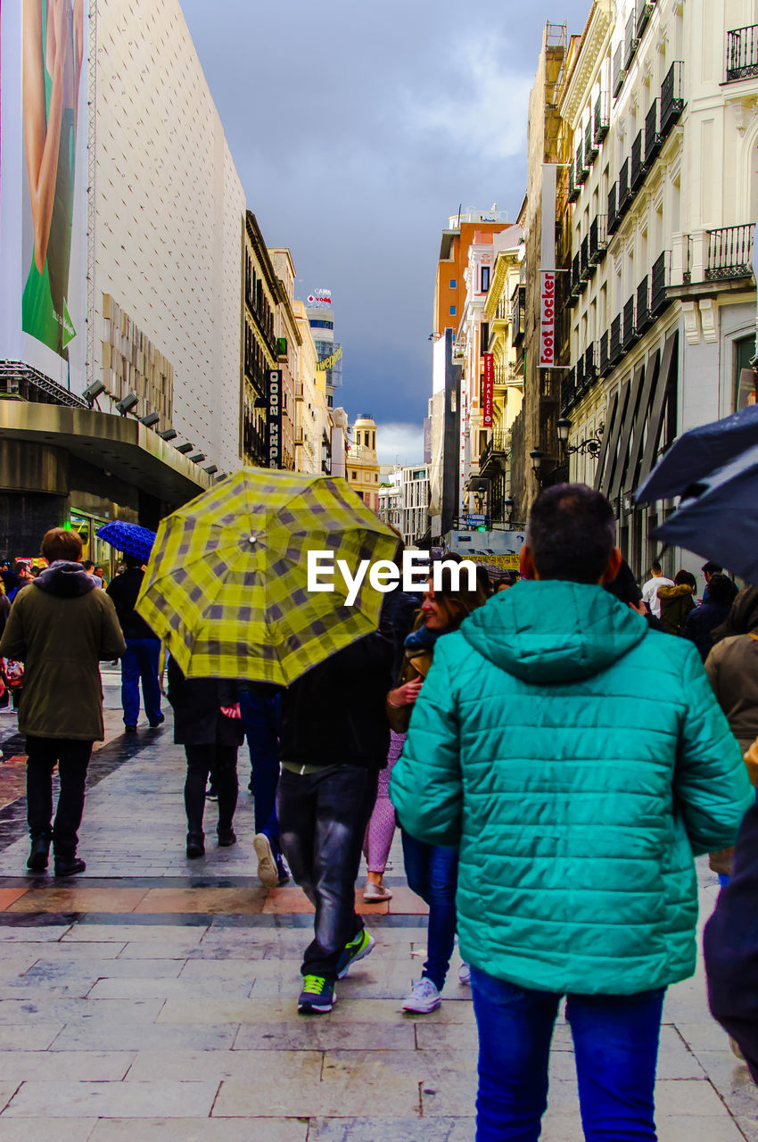 REAR VIEW OF PEOPLE WALKING ON CITY STREET