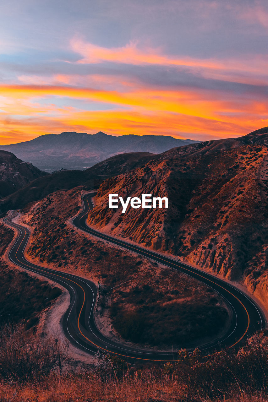 Winding road against sky during sunset