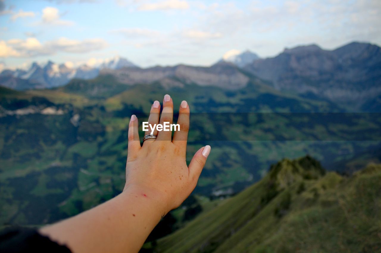 Cropped hand of woman against mountain range