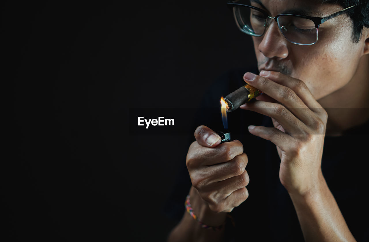 close-up of man smoking cigarette against black background