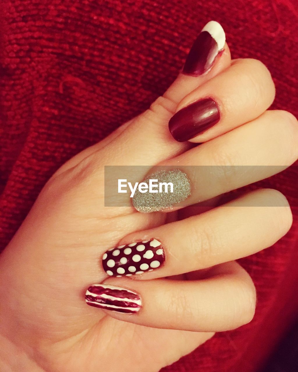 Cropped hand of woman with nail art against red fabric