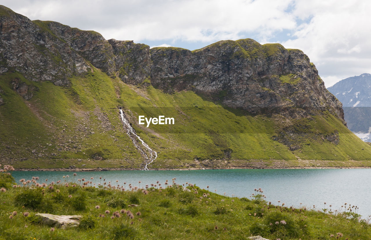 scenic view of lake by mountains against sky