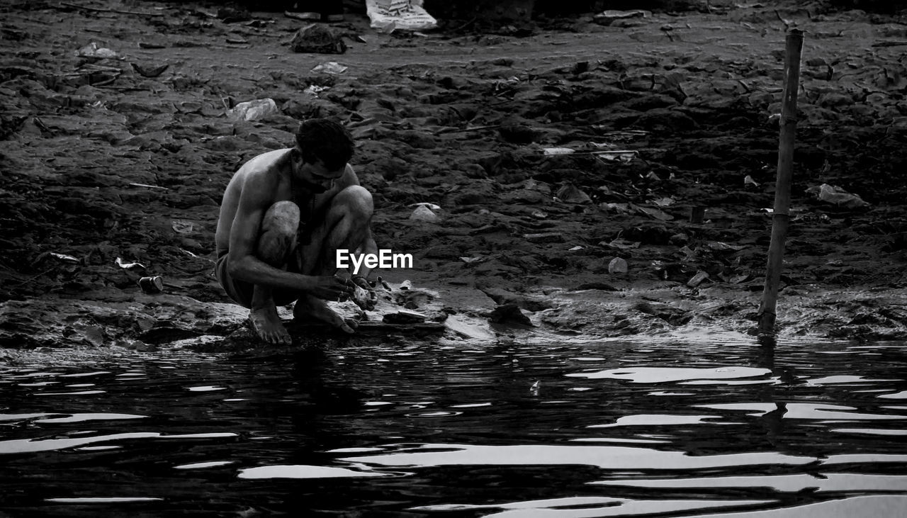 MEN SITTING ON LAKE SHORE