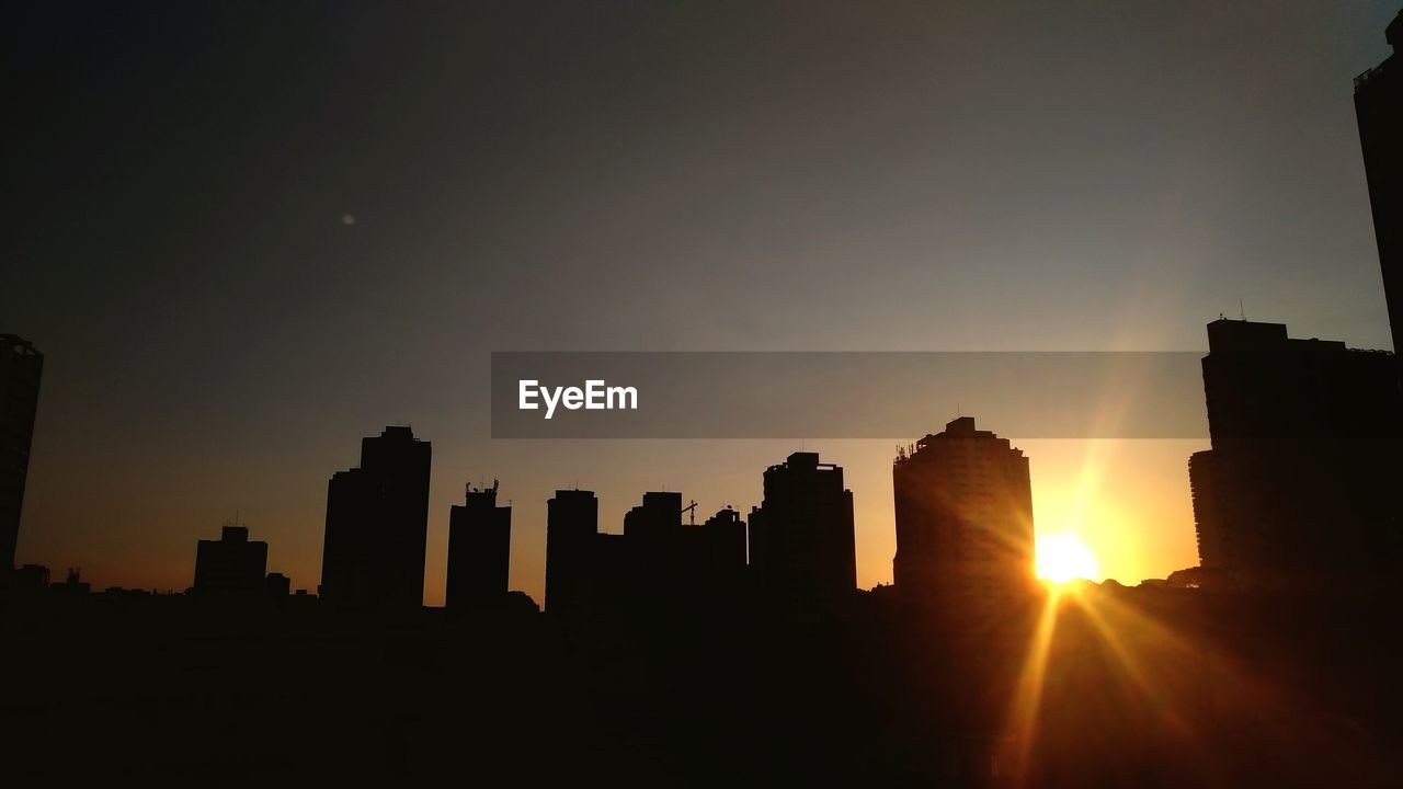 SILHOUETTE BUILDINGS AGAINST SKY AT SUNSET