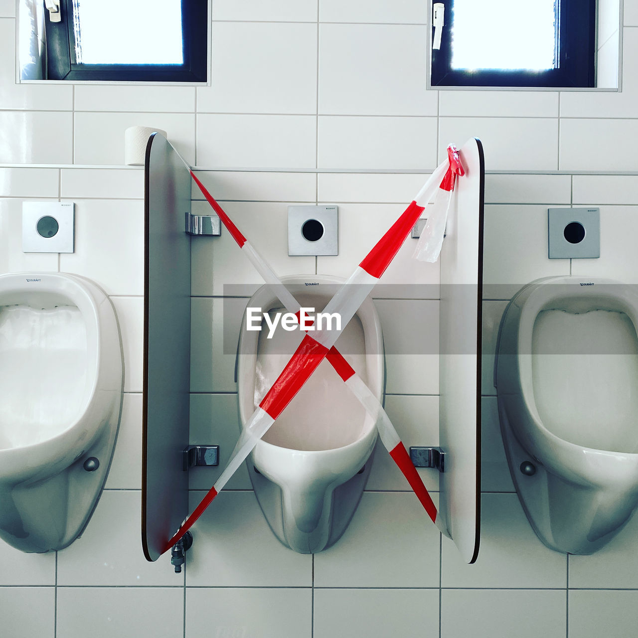 Empty urinal with social distancing sign