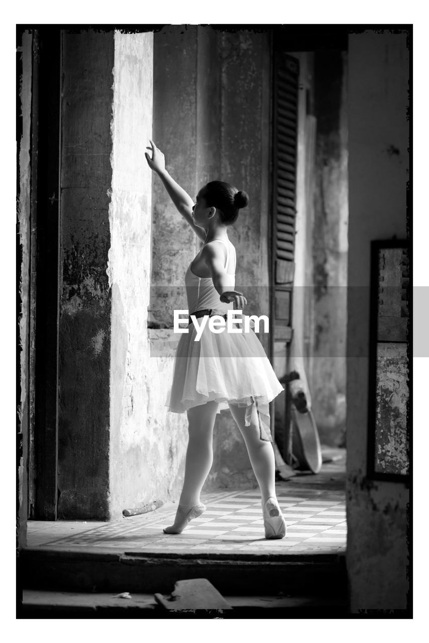 Ballet dancer tiptoeing in abandoned building corridor