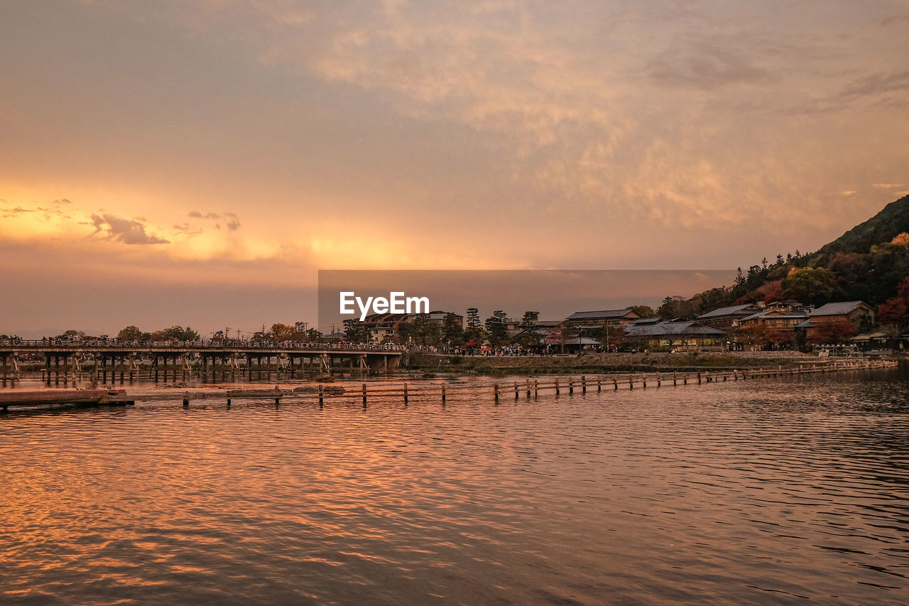 SCENIC VIEW OF SEA AND BUILDINGS AGAINST SKY DURING SUNSET