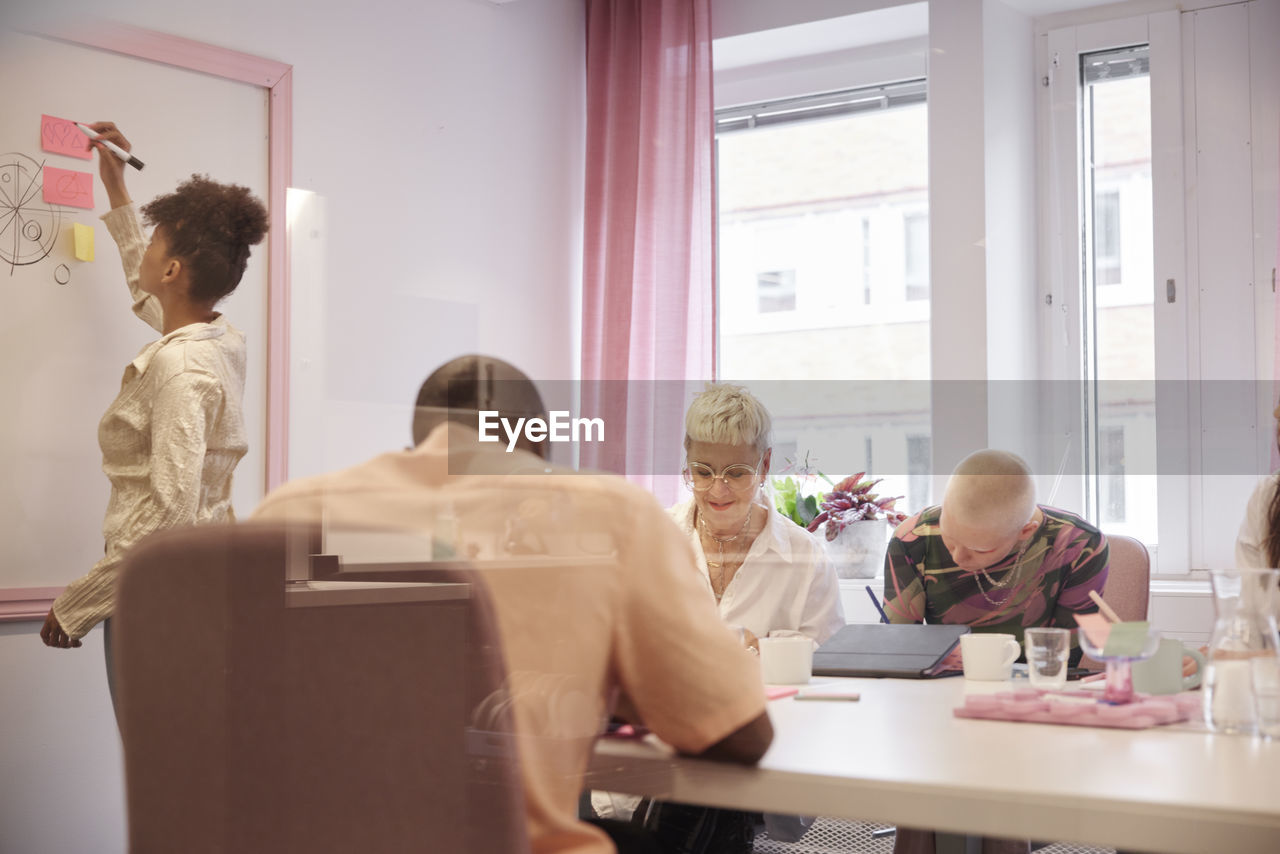 Coworkers having business meeting, woman writing on whiteboard