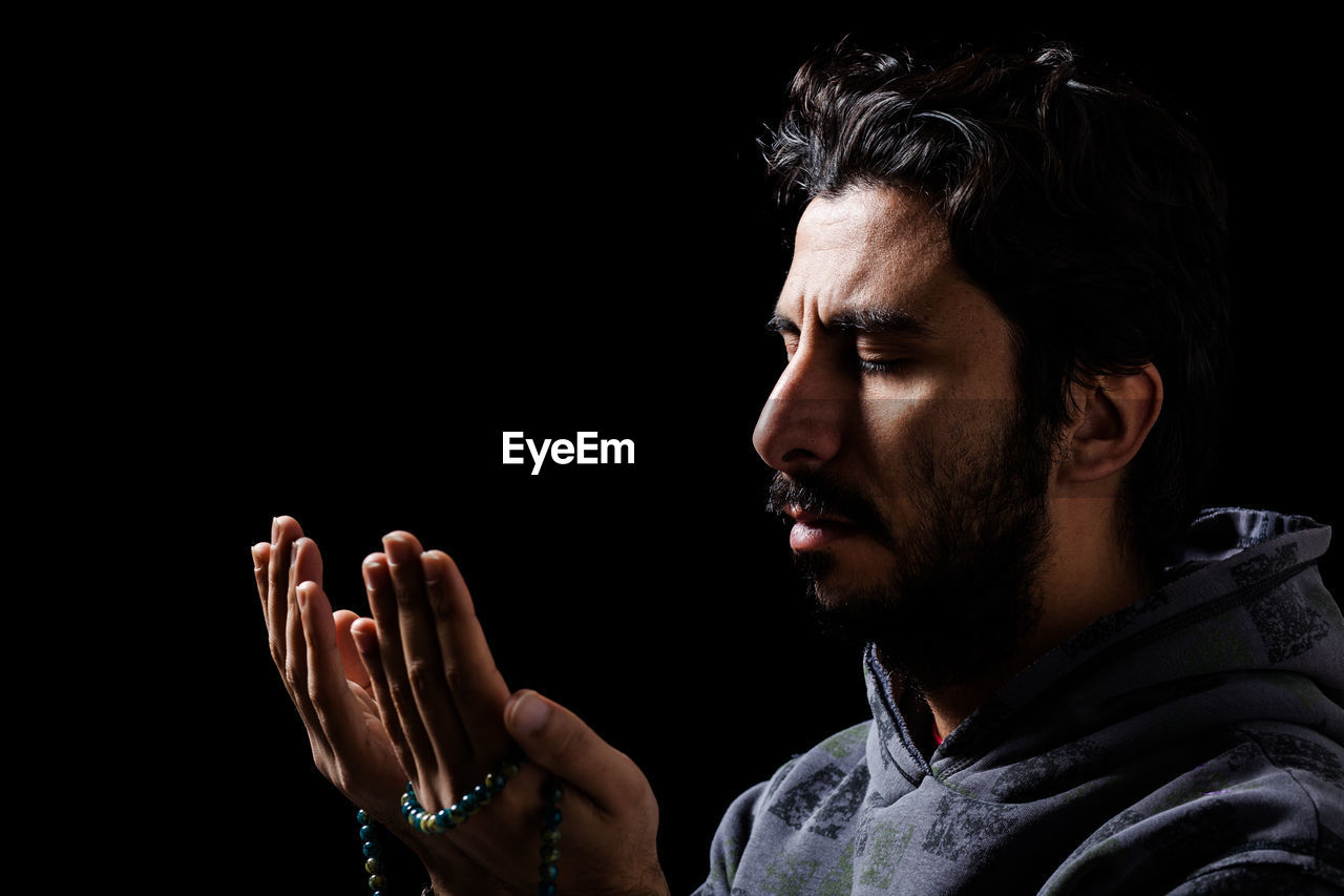 PORTRAIT OF YOUNG MAN AGAINST BLACK BACKGROUND