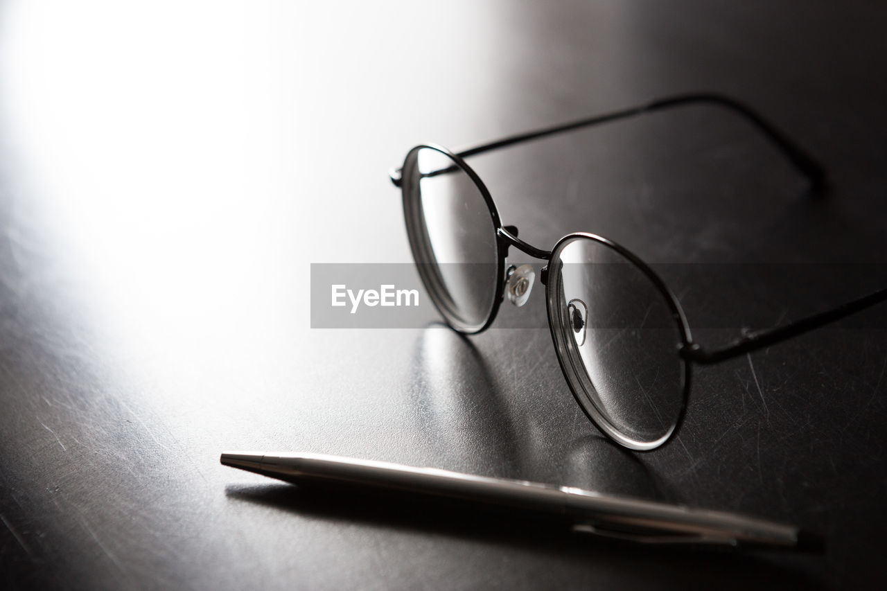 CLOSE-UP OF EYEGLASSES ON GLASS TABLE