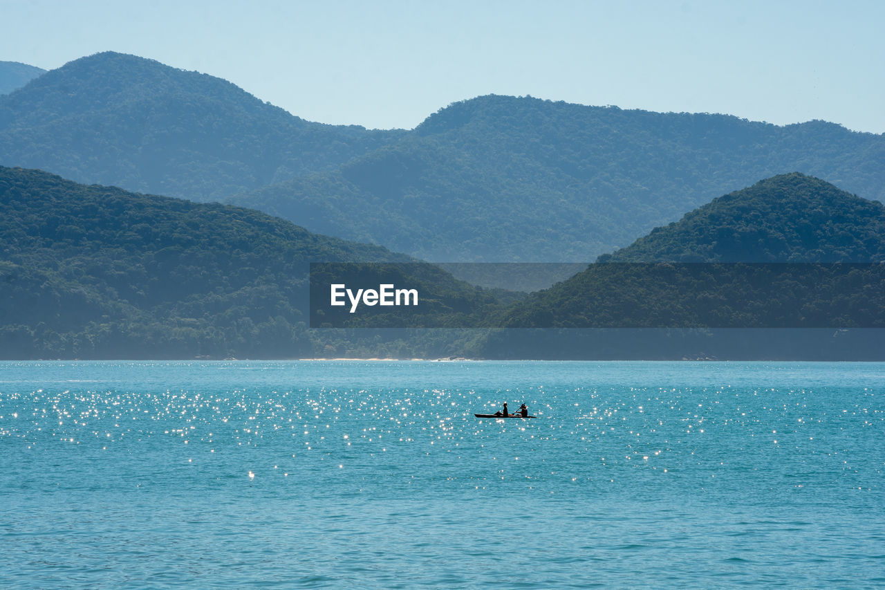 SCENIC VIEW OF SEA AGAINST MOUNTAIN RANGE