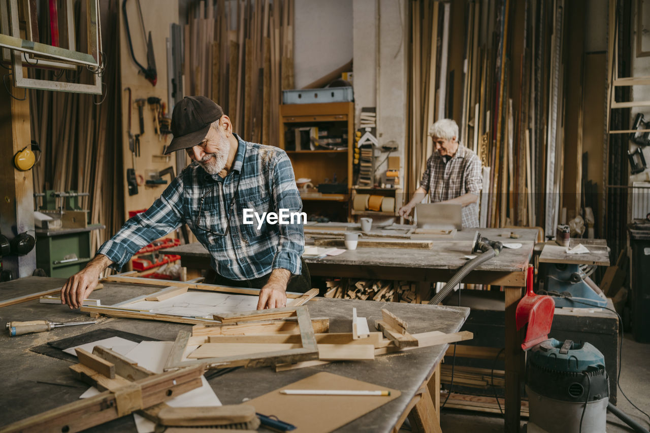 Senior craftsman preparing frame on workbench at repair shop
