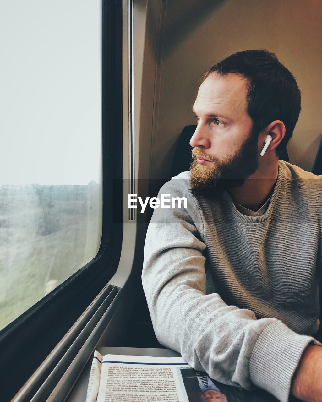 PORTRAIT OF YOUNG MAN LOOKING THROUGH WINDOW AT TRAIN