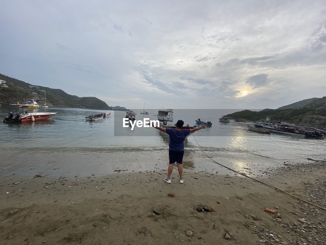 REAR VIEW OF MAN PHOTOGRAPHING AT BEACH