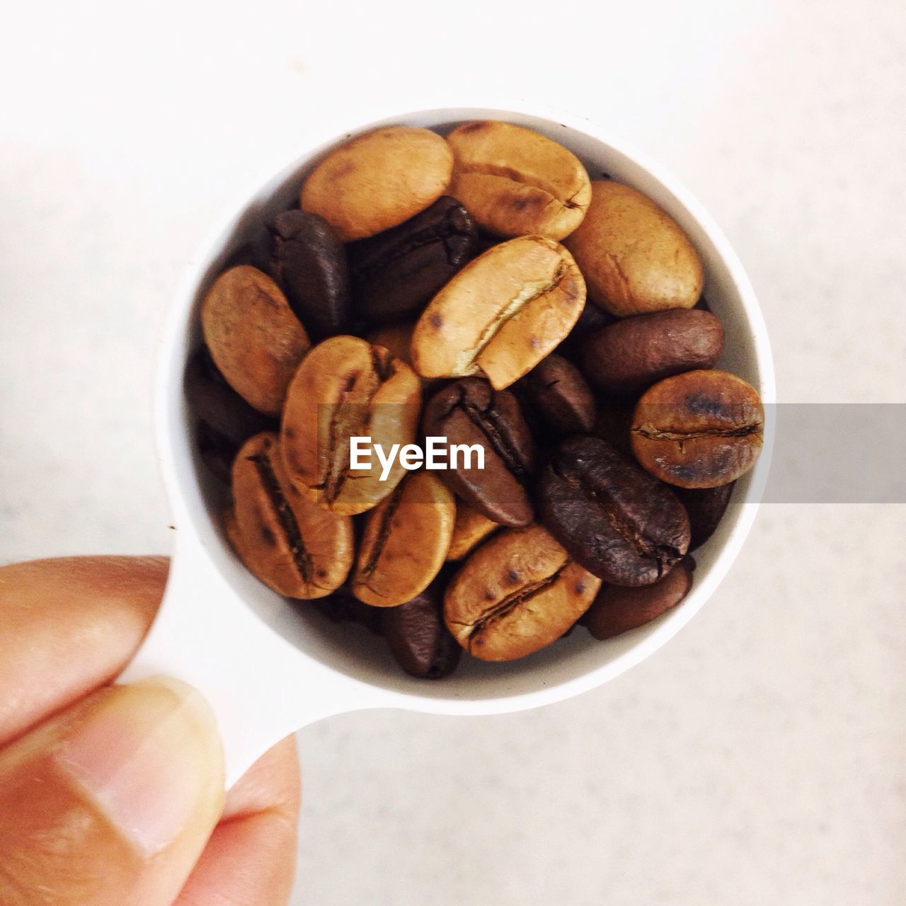 Cropped hand holding bowl with roasted coffee beans