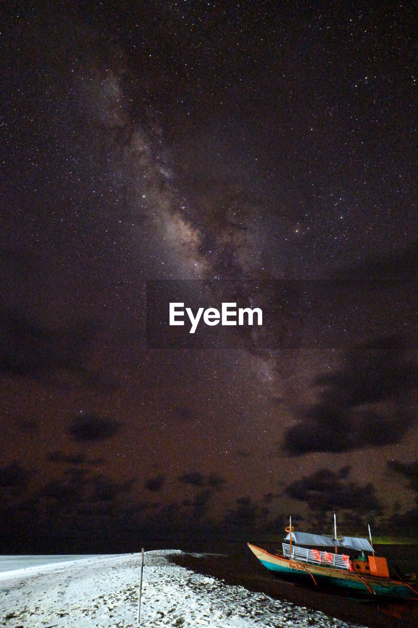 Boat moored at sea against sky at night