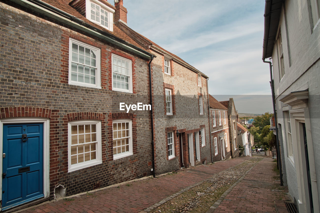 View down historic cobbled keere street with bright blue front door in foreground lewes sussex uk