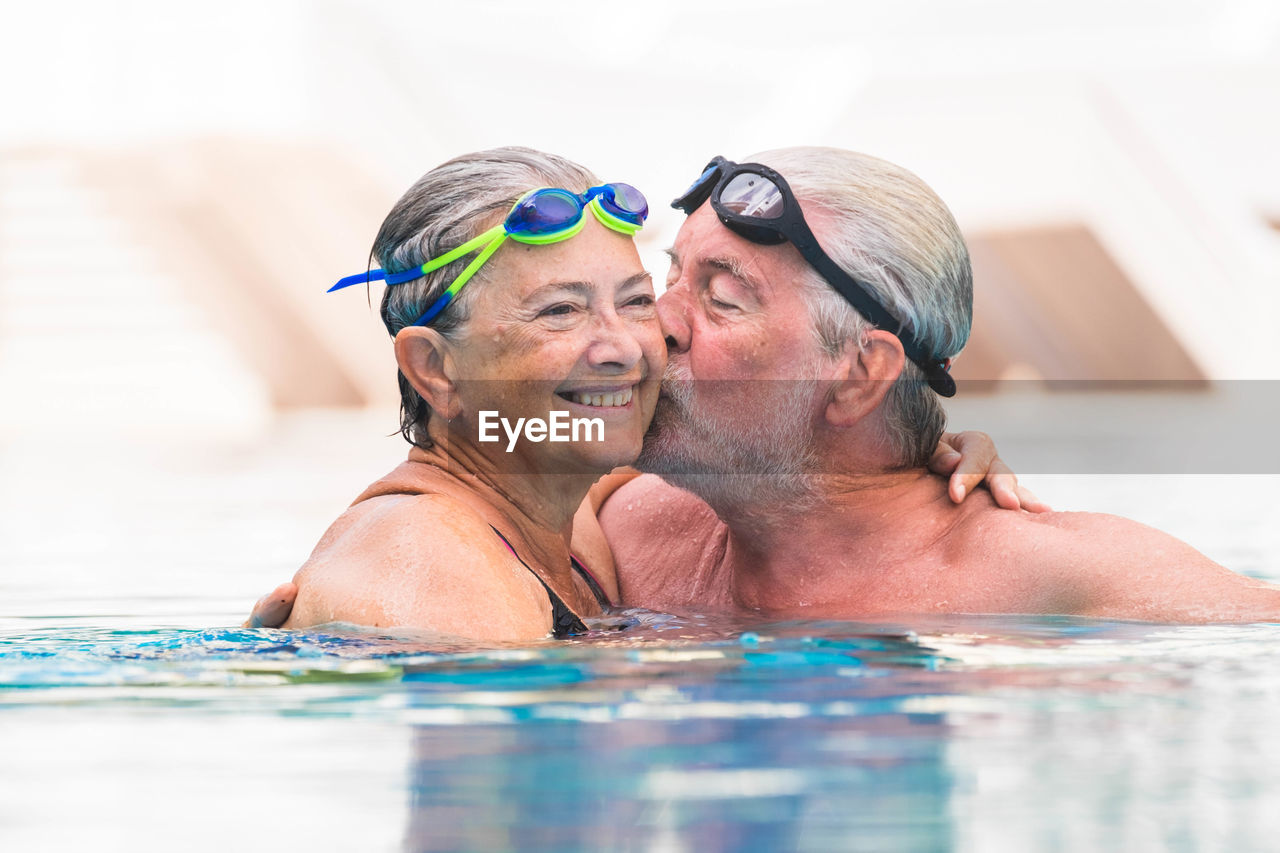 Senior man kissing woman in swimming pool