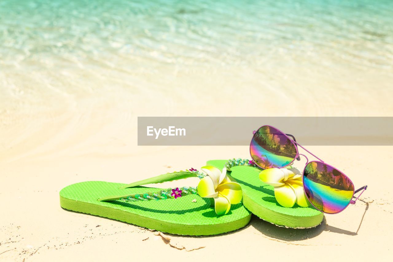 Green flip plops and rainbow sunglasses by the sea