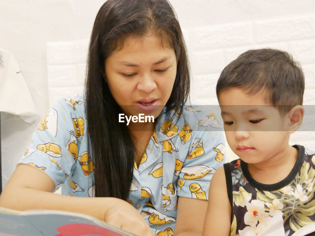 Mother reading book with daughter at home