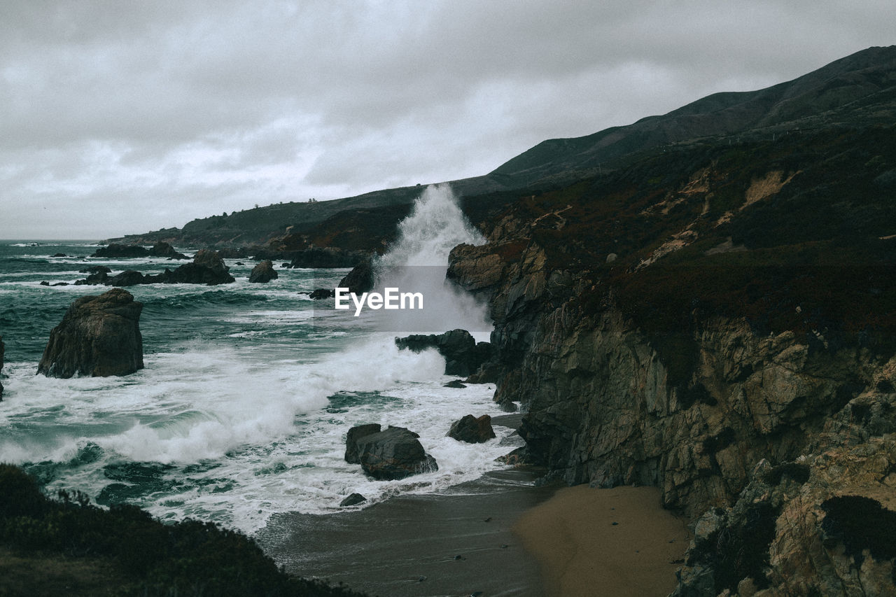 SCENIC VIEW OF SEA AGAINST ROCKY MOUNTAINS