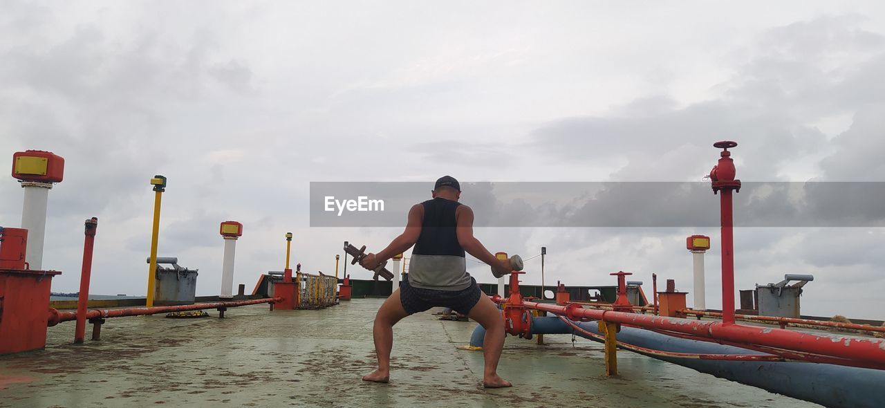 Rear view of man standing by sea against sky