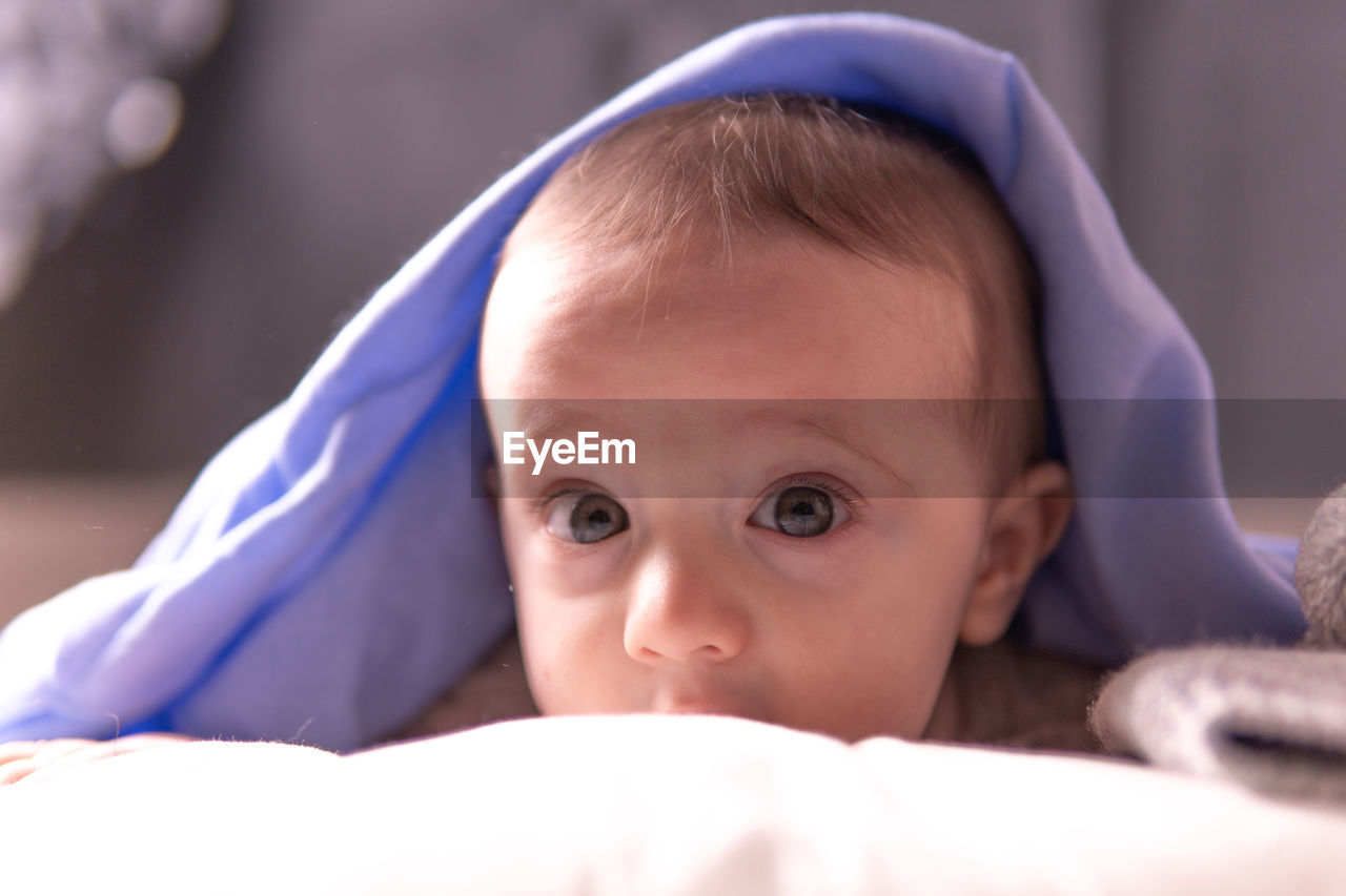 Close-up portrait of cute baby lying down on bed