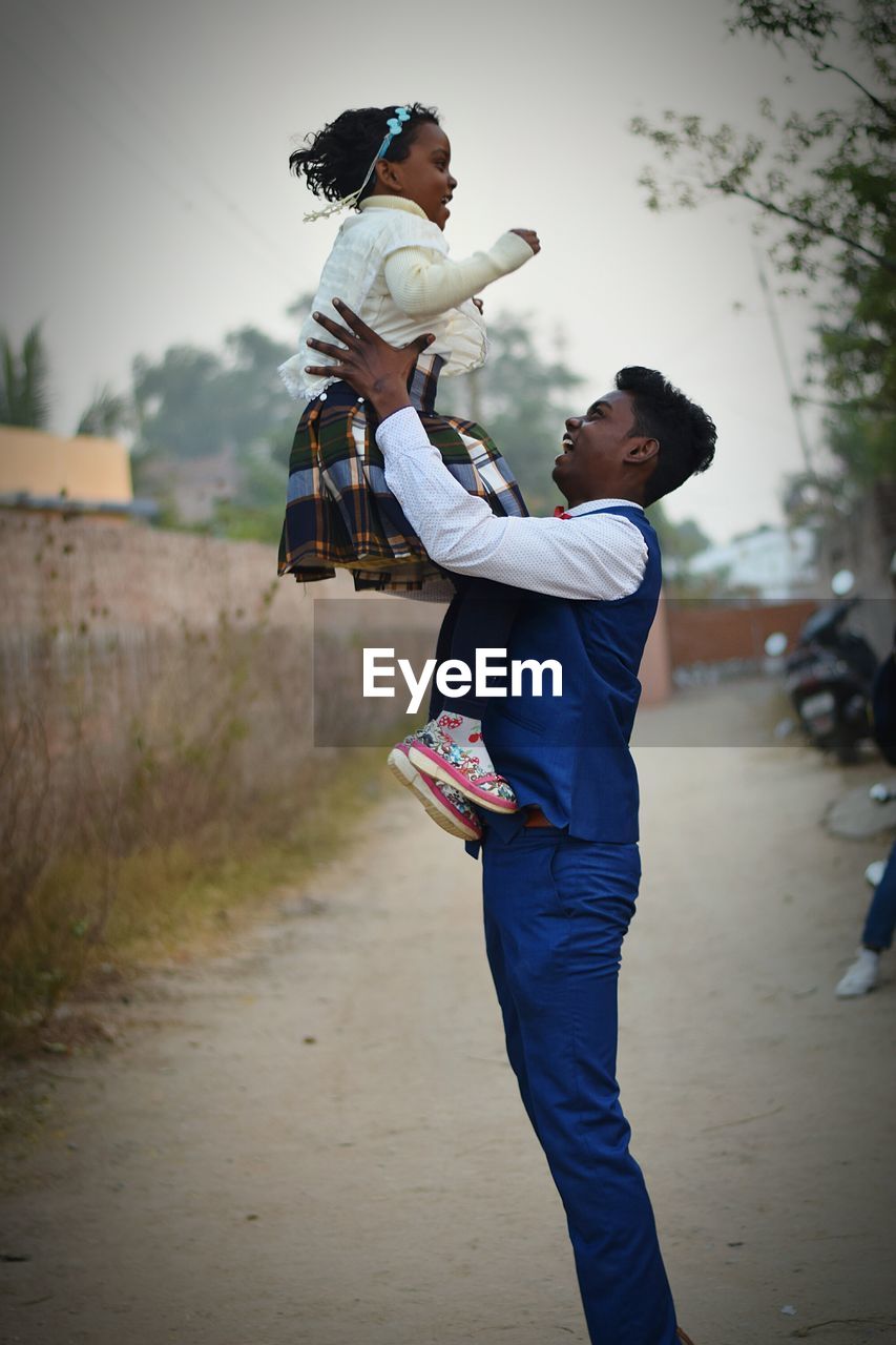 Side view of young man holding sister on road