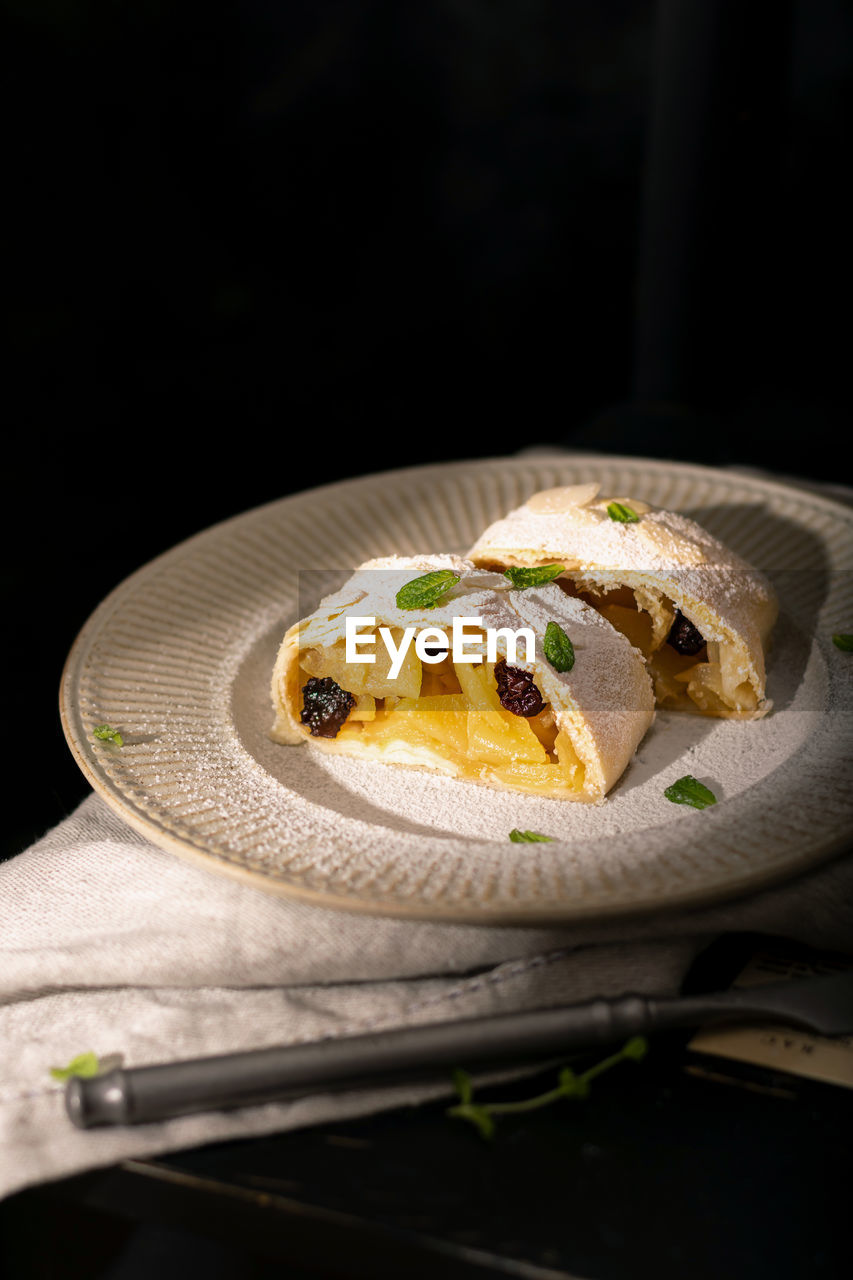 Close up of apple austrian strudel with cinnamon and mint on a plate