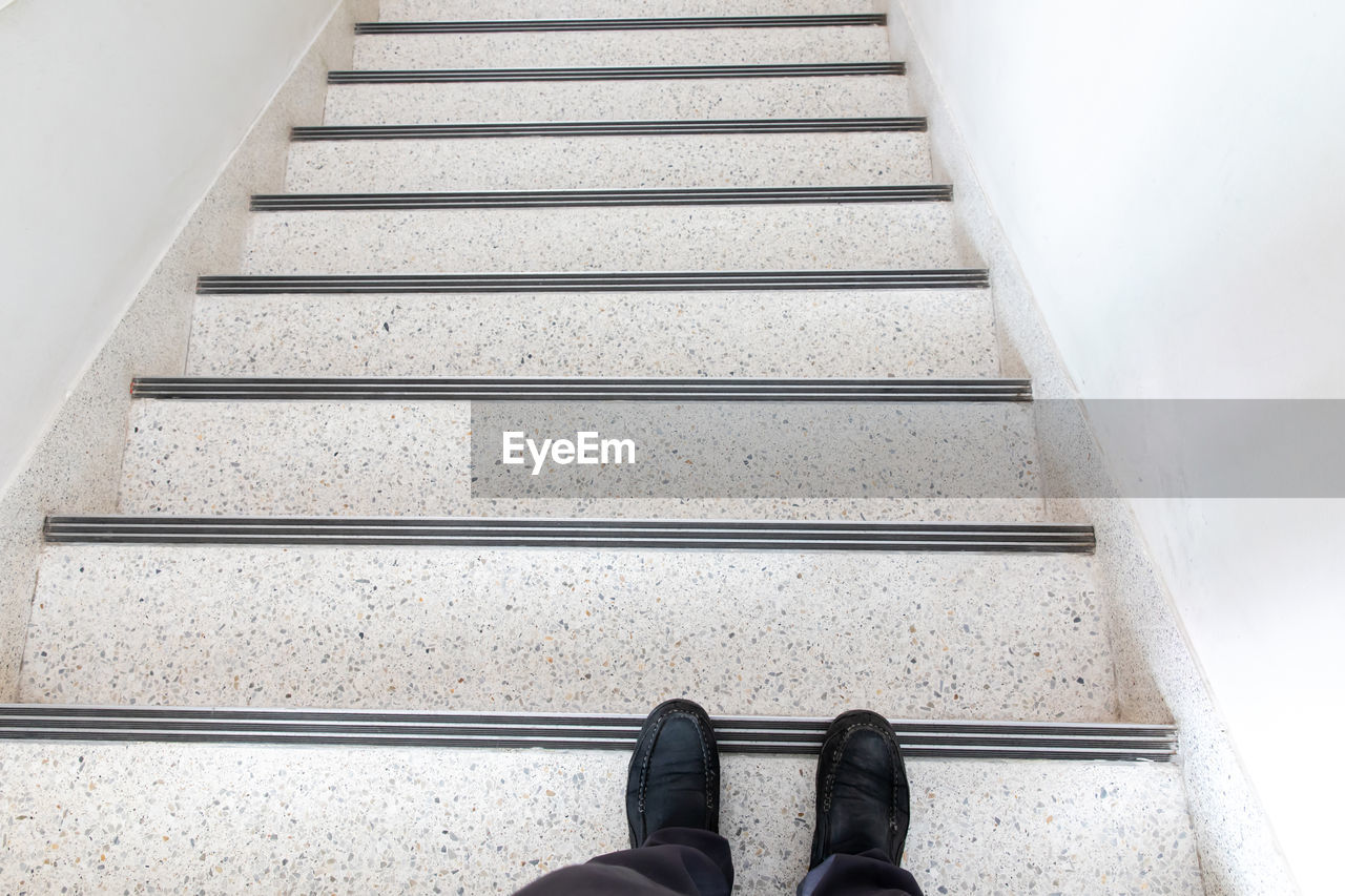 LOW SECTION OF WOMAN STANDING ON STAIRCASE