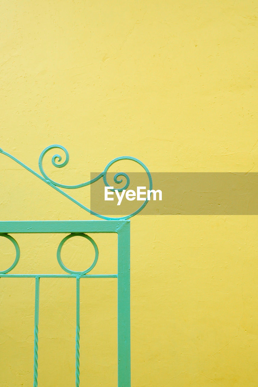 Close-up of gate on yellow wall