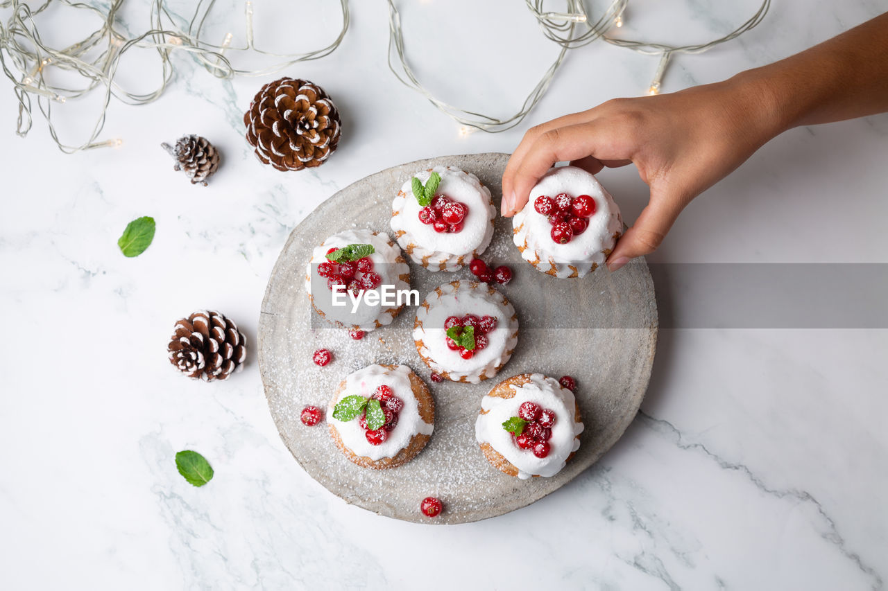 Cropped hand of woman holding christmas muffin on table