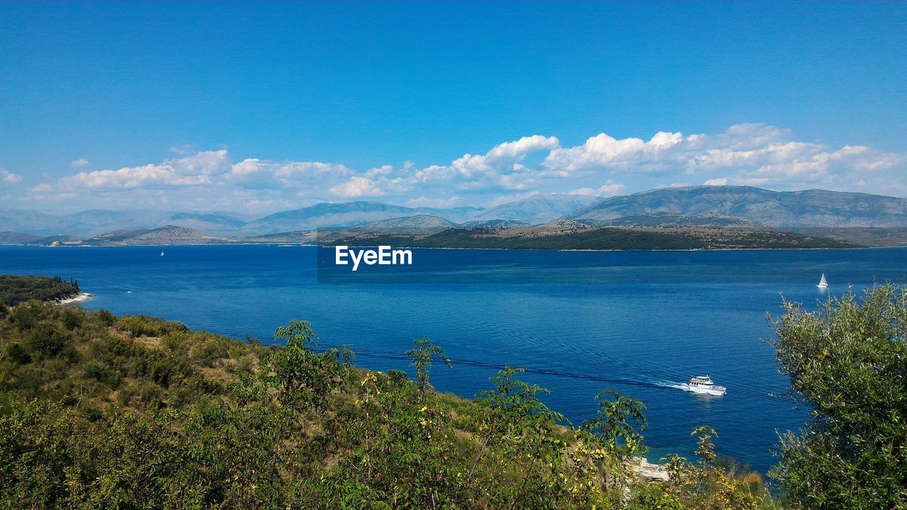 SCENIC VIEW OF SEA BY MOUNTAINS AGAINST BLUE SKY