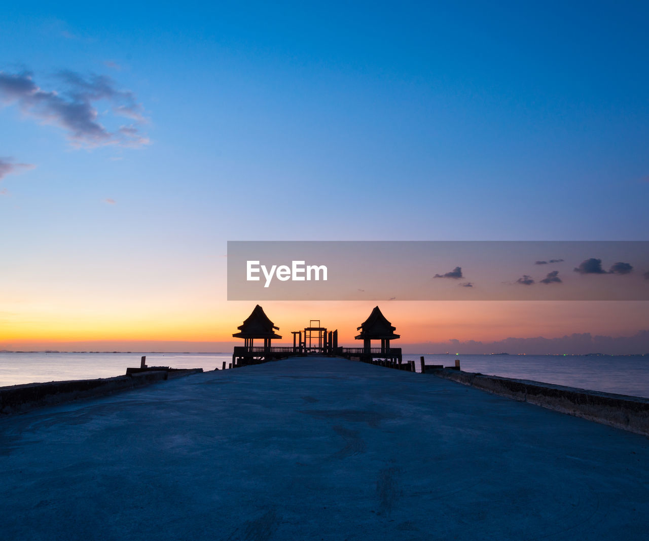 Pier in sea against sky during sunset