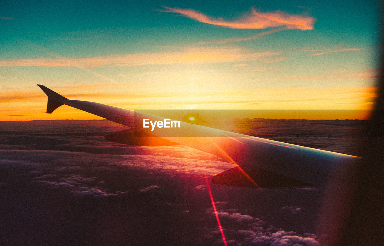 CROPPED IMAGE OF AIRPLANE WING OVER CLOUDS