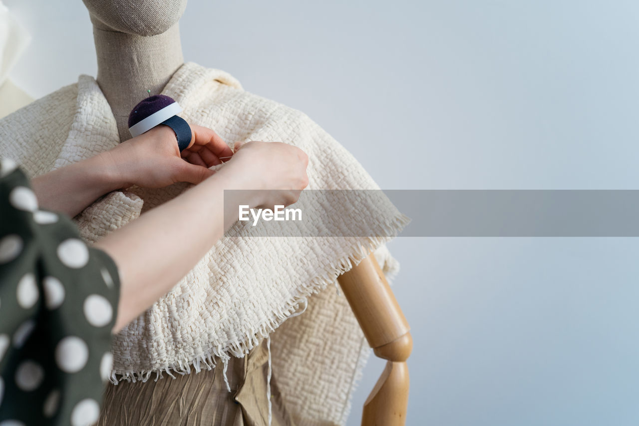 Cropped image of woman adjusting fabric on mannequin