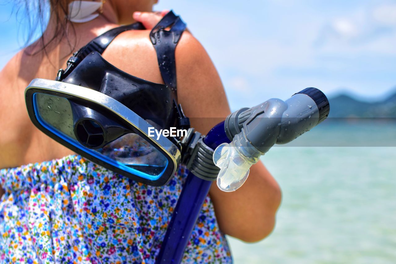 Midsection of woman with scuba mask in sea