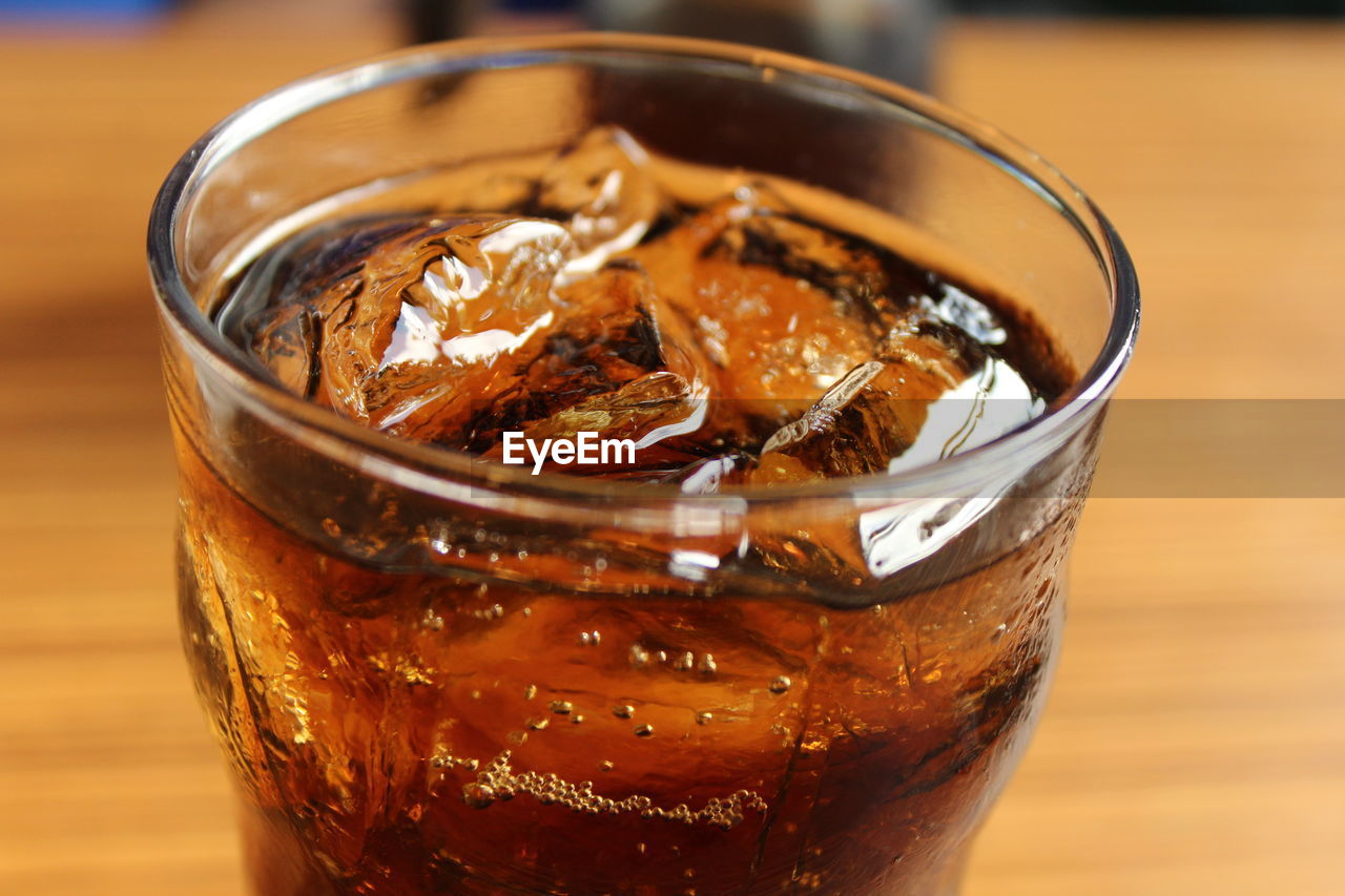 Close-up of ice cubes in cola on table