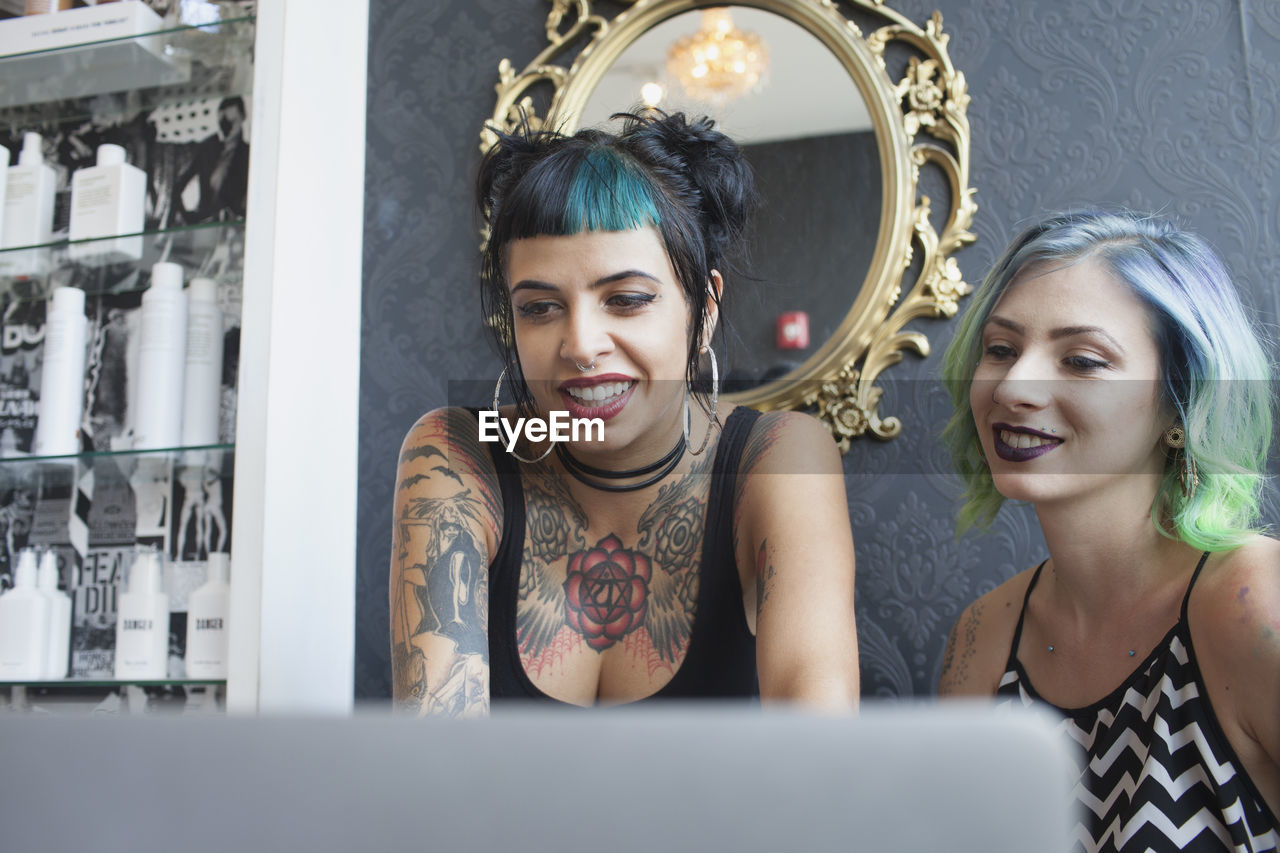 Two young woman smiling at a laptop.