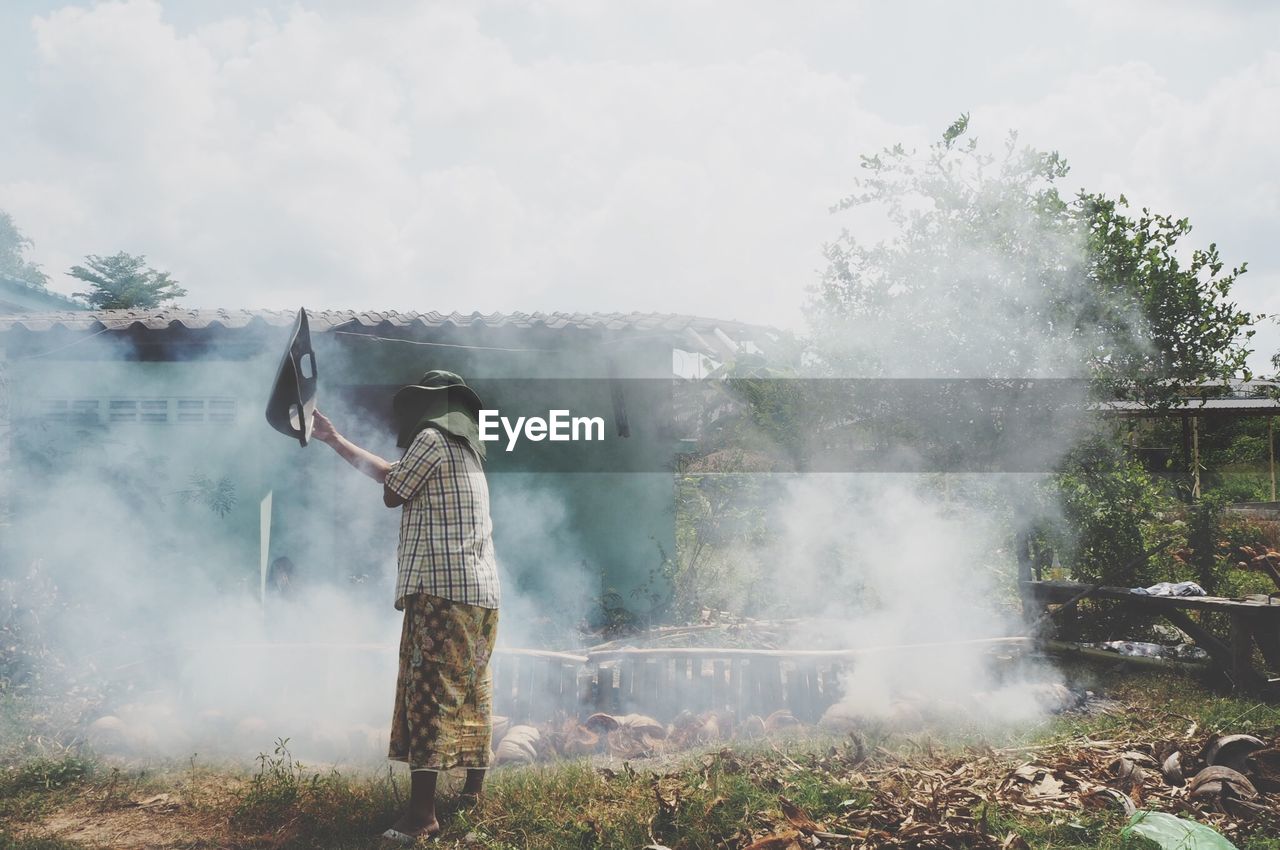 Man waving smoke while standing on land