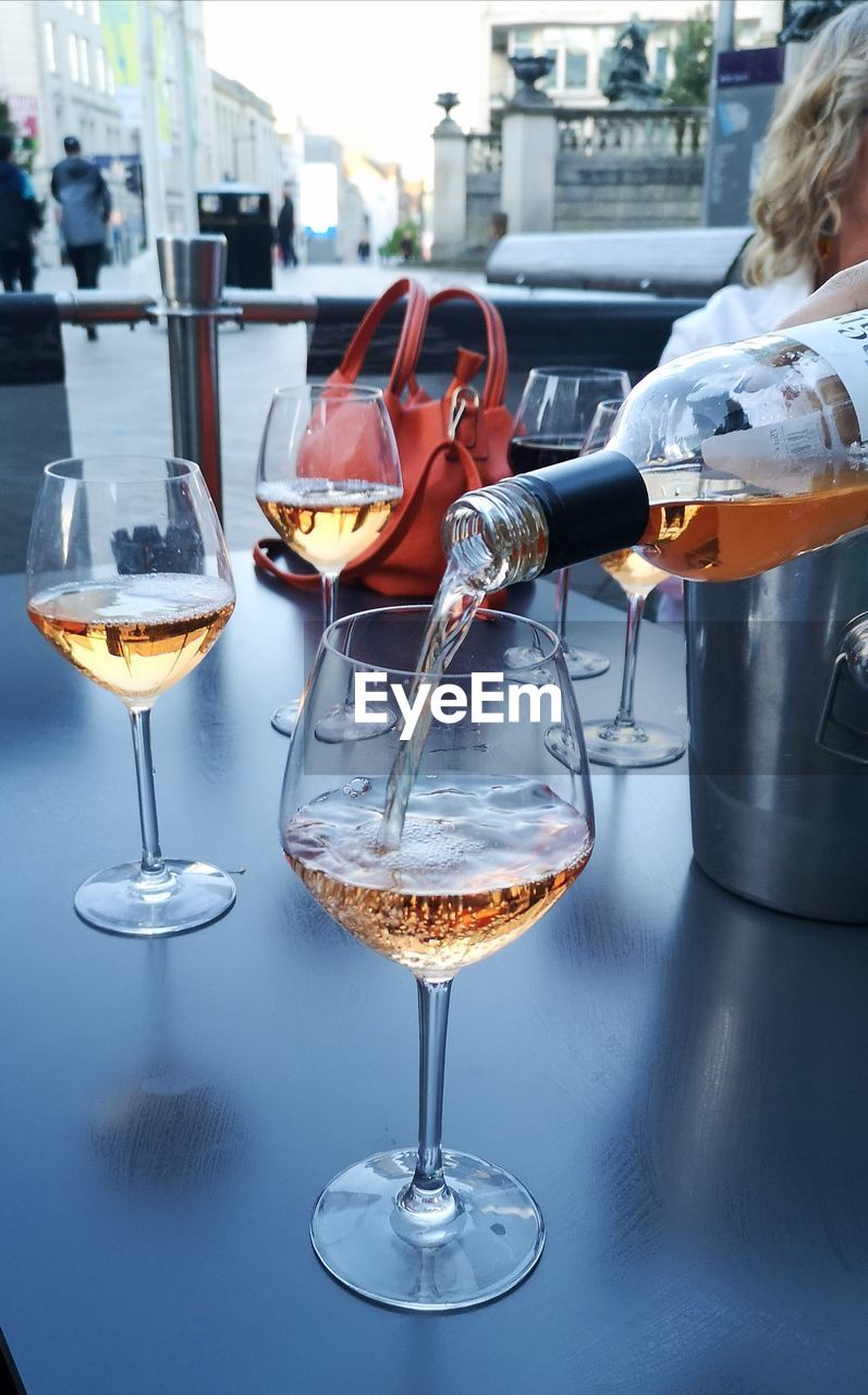 Close-up pouring wine out of a bottle into wine glass on a table