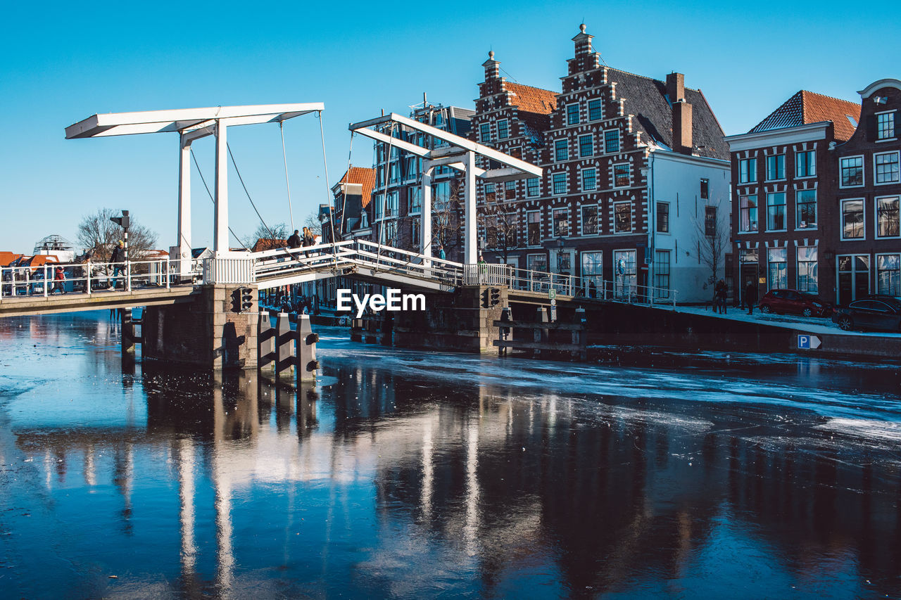 Reflection of buildings in river against blue sky