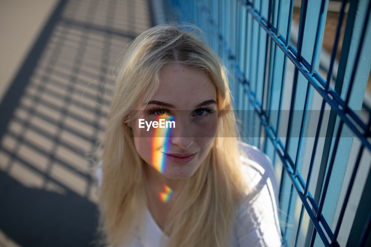 Portrait of young woman sitting by railing