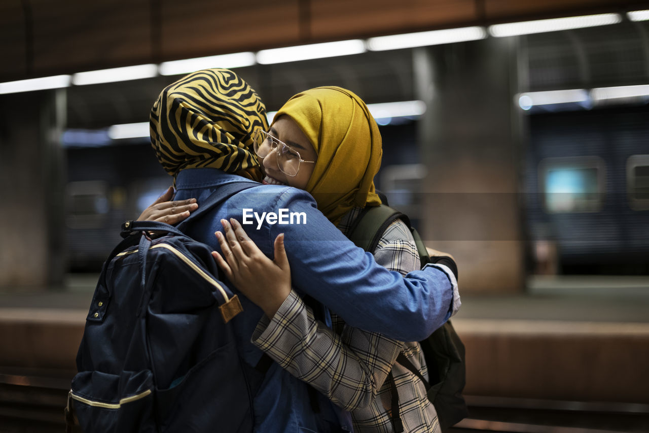 Female friends hugging on train station platform