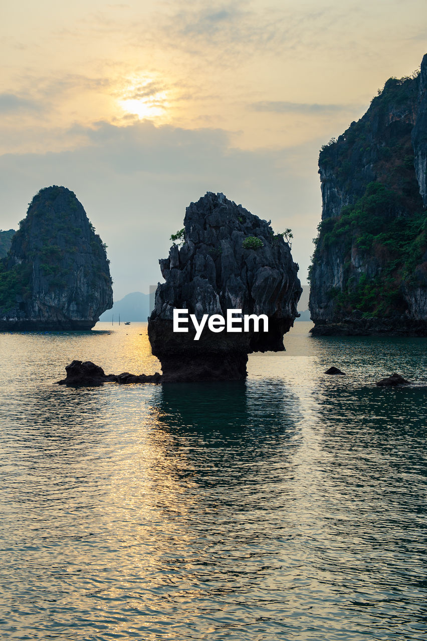 Rock formation in sea against sky during sunset