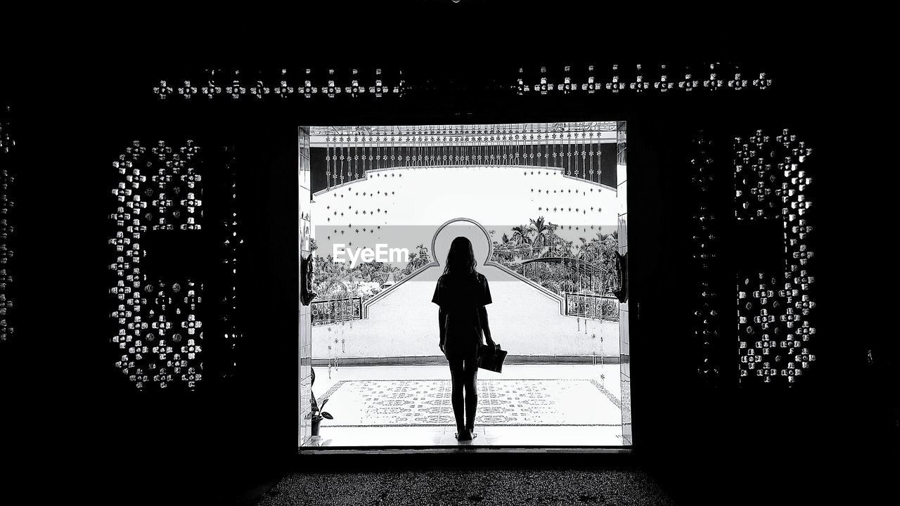 Full length rear view of woman standing in door