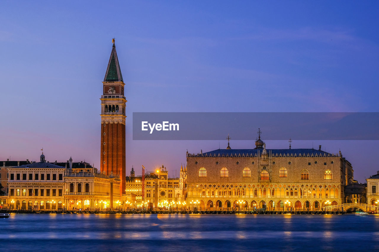 Low angle view of san marco campanile by river against sky at dusk